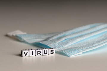 VIRUS is a word written on a white block. VIRUS is the word for your design, concept. Face mask in the background