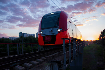 An electric train moving at high speed against the background of sunset.