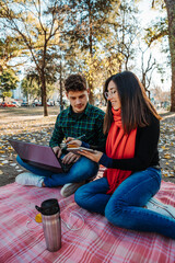 young couple using laptop to work outdoors