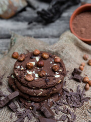 Chocolate cookies with hazelnuts , cocoa and pieces of dark chocolate on the rustic kitchen table