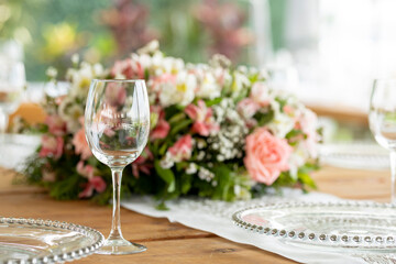 Copa de cristal sobre una mesa con un arreglo floral en una jardín para un evento social en México 