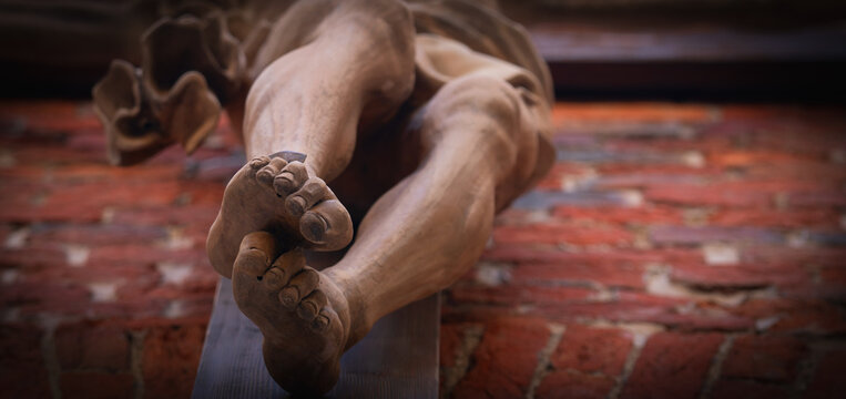 Bottom view of the crucifixion of Jesus Christ. Antique statue. Selective focus on foot sole. Horizontal image. Close up.