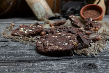 Chocolate cookies with hazelnuts , cocoa and pieces of dark chocolate on the rustic kitchen table