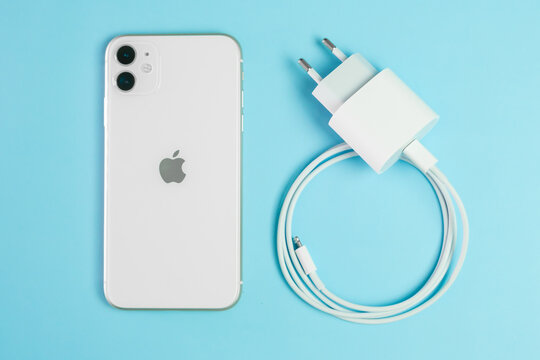 Iphone 11 and adapter for charging on the blue background, June 2021, San Francisco, USA