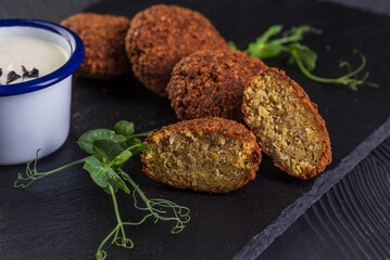 Falafel with garlic sauce on a black stone tray. Vegan food