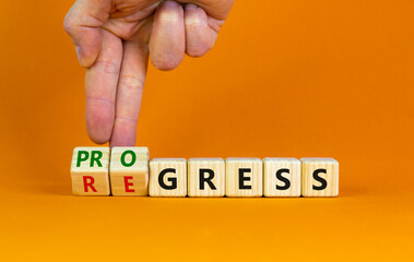 Regress or progress symbol. Businessman turns wooden cubes and changes the word 'regress' to 'progress'. Beautiful orange table, orange background, copy space. Business, regress or progress concept.