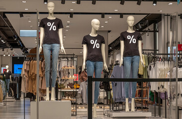 Obraz na płótnie Canvas Seasonal sale. Mannequins wearing black t-shirts with percent sign standing inside clothing store during shopping sale period