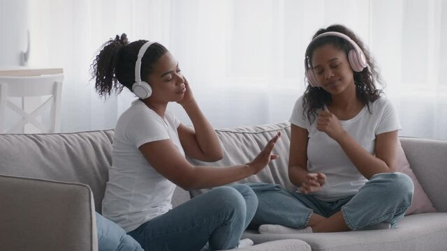 Common sisters hobby. Young woman and teenage girl enjoying great sound of modern music in wireless headphones