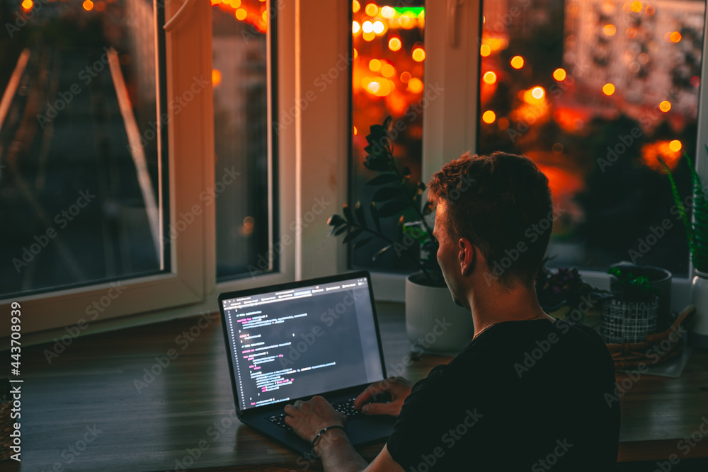 Sticker a young male developer is programming a code script late at night with beautiful city lights at nigh