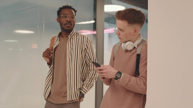 Medium slowmo of arrogant Afro American high school or university student intimidating classmate in corridor