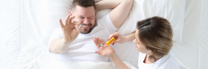 Obraz na płótnie Canvas Woman giving man pill in bed top view