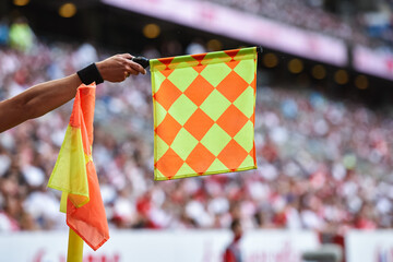 Hand of assistant of football referee with raised flag.