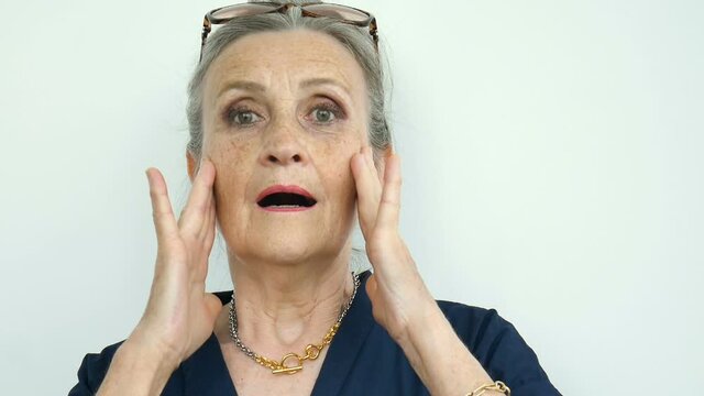 Indoors portrait of anxious shocked senior woman under shock with both hands on face due to fear and stress over white background, stressful retirement, bad news