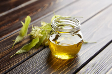 Honey in jar with linden flowers on wooden background
