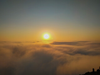 The sun shining above the clouds on a cliff