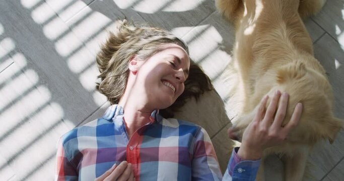 Caucasian woman smiling and lying on floor with dog