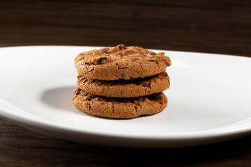 Plate of freshly baked chocolate chip cookies. Wooden background, selective focus