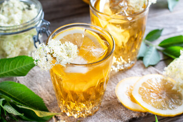 Elderberry flowers and lemon drink. Refreshing healthy summer juice. Glass of elderflower lemonade on wooden board. Alternative medicine and therapy.