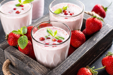 Glass of freshly made strawberry smoothie on wooden background. Healthy food and drink concept