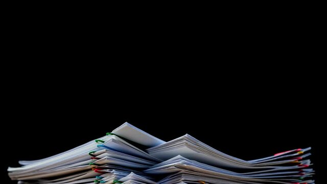 Stack of overload document report paper with colorful paperclip on black background, Bureaucracy business concept footage paperless used &ndash; 4K Stop motion. Key frame technique