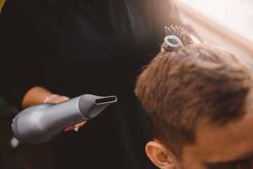 Master woman barber does hairstyle and styling with dryer hair to guy barbershop
