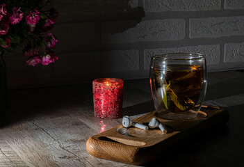 
Mint tea in a thermostat is on the table at night. Against the background of a bunch of small roses.