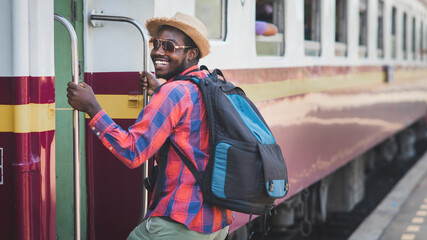 African male traveler with hat and backpack entrain to the train on railway station.Adventure travel concept