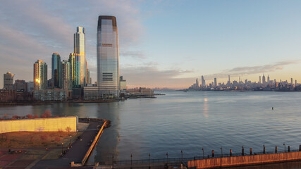 Aerial of New Jersey skyscrapers on the Hudson River across from Manhattan with a 911 memorial in the foreground.