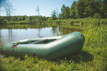 Rubber boat with fishing gear standing on a river near the sandy beach.