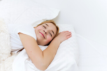 Obraz na płótnie Canvas Peaceful beautiful young lady lying, relaxing, sleeping in cozy white bed on soft pillow resting covered with blanket enjoying good healthy sleep concept