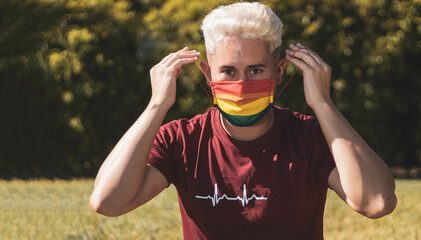 
young gay man removing a mask with the drawing of the rainbow.
Gay pride.
LGTBI.
Liberty