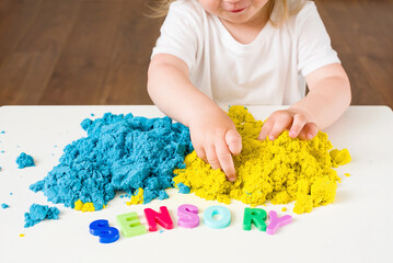 Little girl playing with magic kinetic sand, Sensory word. Early sensory education. Kidd's sensory...