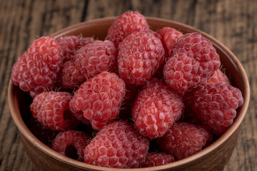 red fresh domestic raspberry at bowl on a rustic table top. space