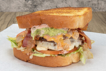 Enormous texas toast sandwich loaded with hamburger, cheese, lettuce, bacon, and special sauce for that huge appetite.