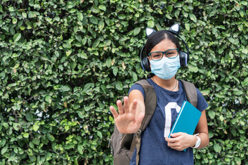 Beautiful student girl with protective mask and backpack holding books with open hand signaling detention