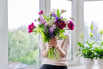 Bouquet of bright flowers of peonies irises lupins in the hands of woman close-up
