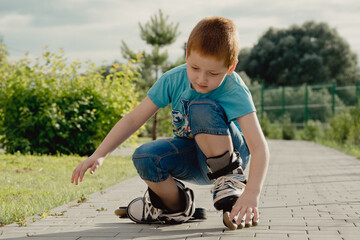 Fototapeta premium A boy tries to get up from the ground after falling with the roller skates. a boy riding a bike or roller, fell and injured his leg