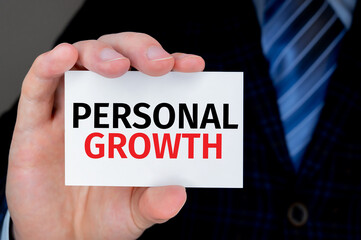 Business and finance concept. PERSONAL GROWTH text on a business card held by businessman
