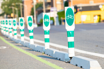 Green reflective safety barriers for bicycle lanes on the street, barriers are in selective focus...