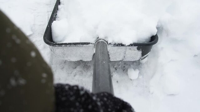Man with a shovel removes snow first person view. cleaning the area near the house after a snowstorm