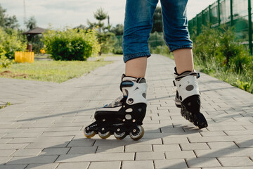 Little boy in protective equipment and rollers stands on walkway in park, low angle view