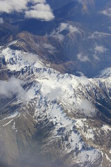 航空機の高度から見下ろした、冠雪した山々と雲