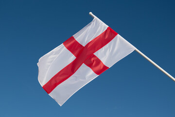 English flag waving in wind. Flag of England on blue sky background.
