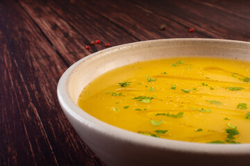 Hot cassava cream broth in a white bowl, on a wooden table (Brazilian caldo de mandioquinha)