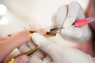 detail of professional manicurist applying glue to glue nail extensions, personal care concept
