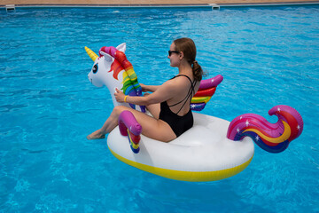 Beautiful woman on unicorn pool float in pool in the hotel. Summer holidays