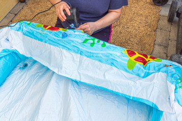 Close up view of woman inflating inflatable pool for children using an electric pump. Sweden. 