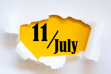 July 11. 11th day of the month, calendar date. Hole in paper with edges torn off. Yellow background is visible through