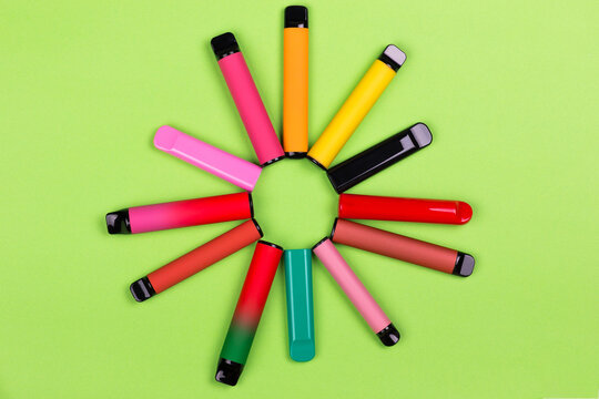 Disposable single pink e-cigarettes with saline nicotine. Pod systems in a sun of different colors. Devices for quitting smoking. Red, yellow, green, pink and black.