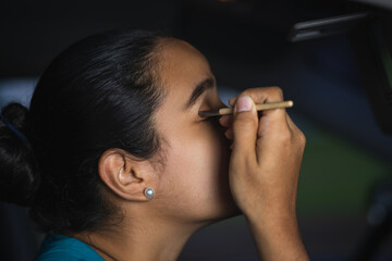 Obraz premium latin woman putting eyeliner in the car while driving